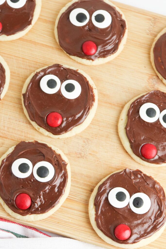 decorated reindeer cookies on wooden cutting board 