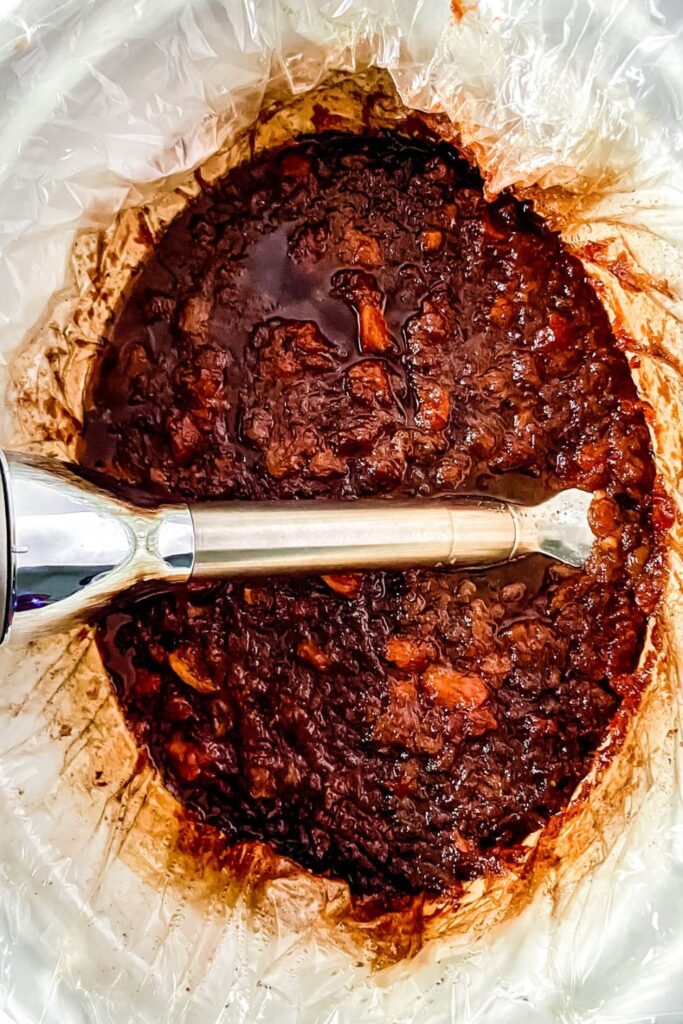 crock pot apple butter with an immersion blender in the crockpot