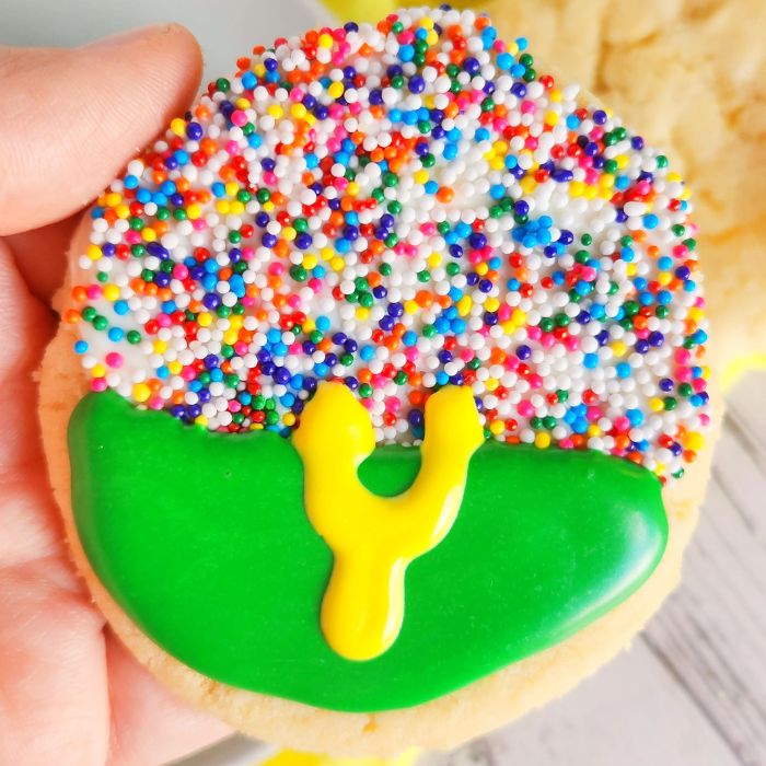 holding a football shaped sugar cookie that looks like a goal post 