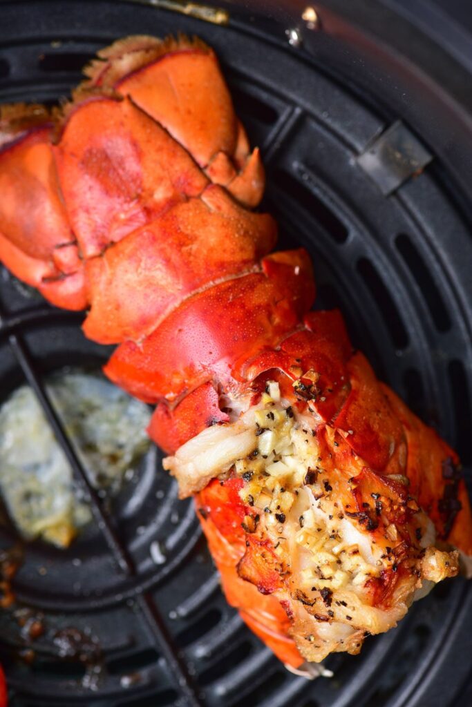 close up of overhead shot of a cooked lobster tail in an air fryer basket