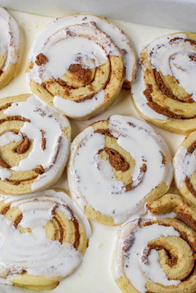 heavy cream poured over raw cinnamon rolls in a casserole dish