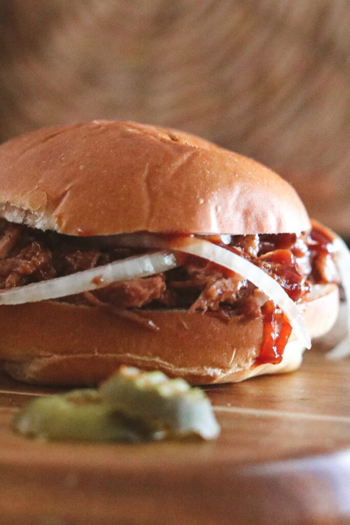 side view of pulled pork with onions on the sandwich
