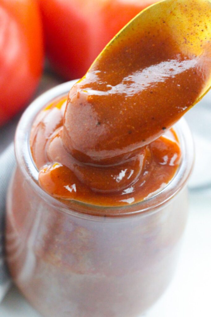 enchilada red sauce in jar with a spoon with some sauce 