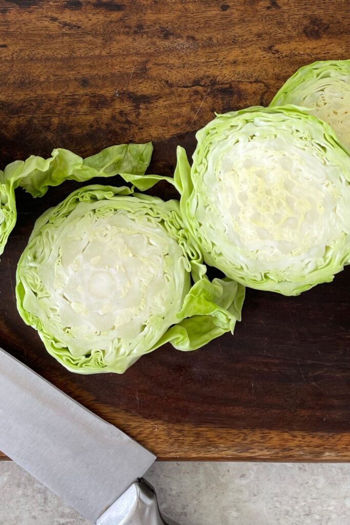 sliced cabbage steaks on a wooden cutting board