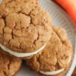 carrot cake sandwich cookies stacked on a white plate on table