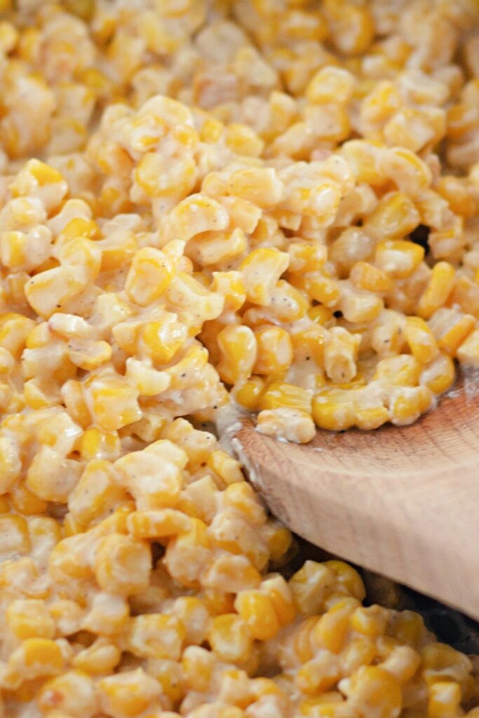 corn in a pan with a wooden spoon on the side of bowl
