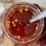 overhead shot of honey with red pepper flakes in it and a spoon in the bowl