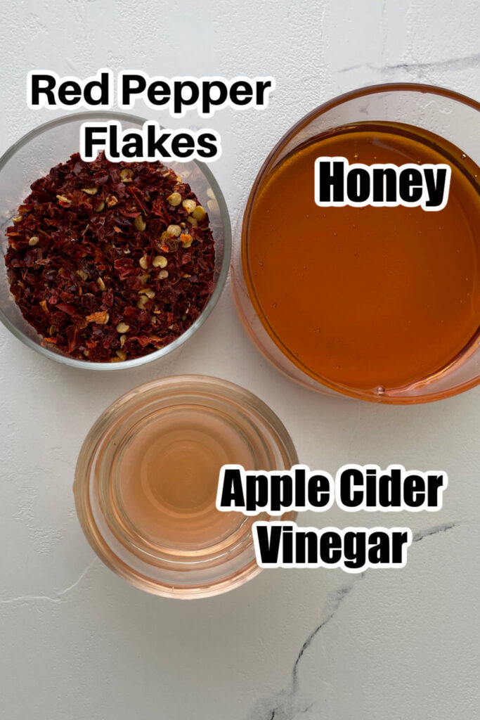 honey, pepper flakes, and vinegar on a marble counter 