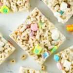 Lucky Charms Rice Krispie Treats on a white counter with pieces of cereal around it