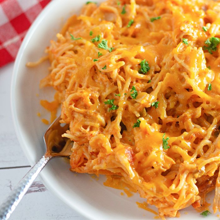 white plate with chicken spaghetti on it with a fork on it 