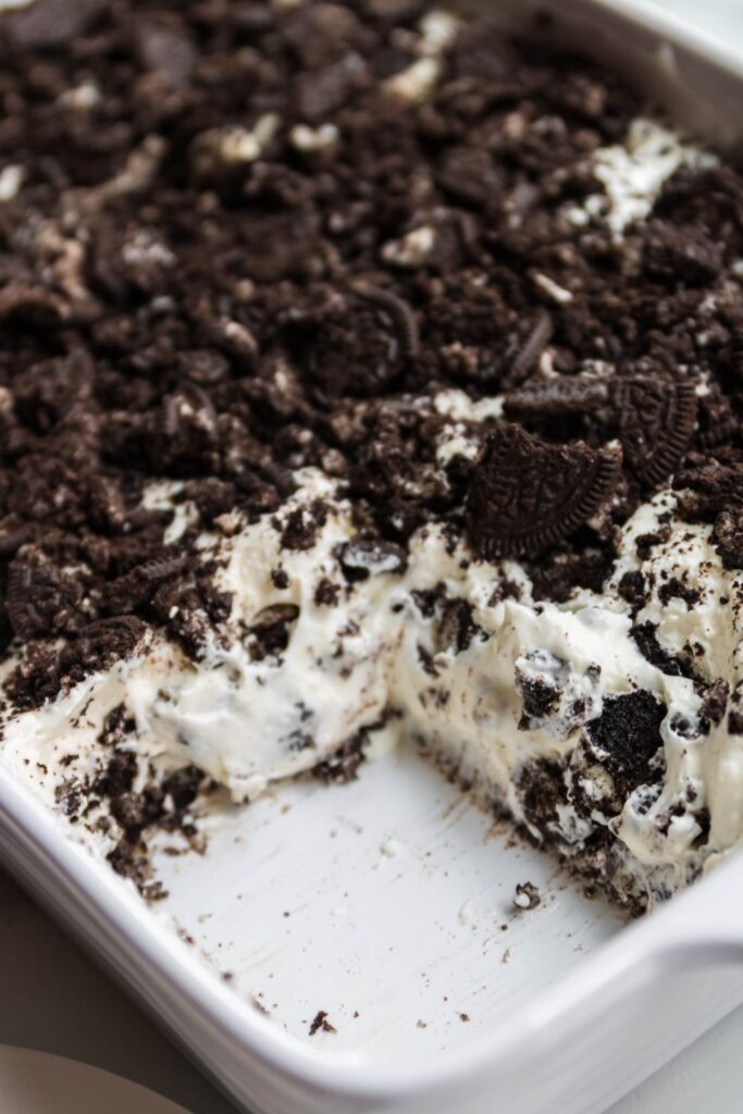 sliced Oreo dessert in a casserole dish with piece taken out 