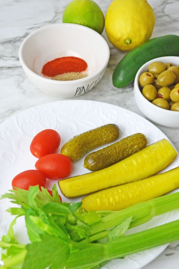 celery, pickles, tomatoes on plate and lime and lemon in background 