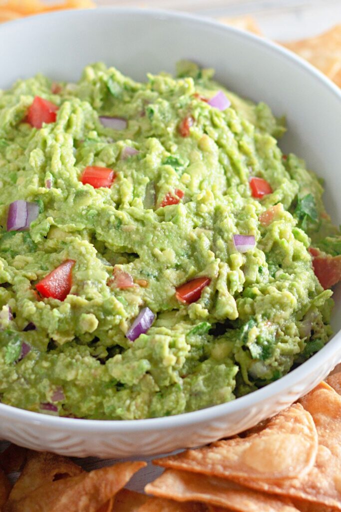 bowl of guacamole with chips around the bowl on a platter 