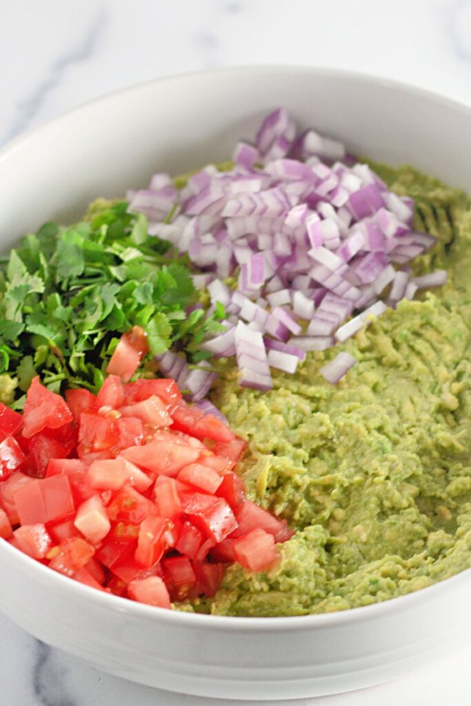 bowl with guacamole ingredients chopped on top 