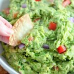 a chip being dipped into a bowl of guacamole