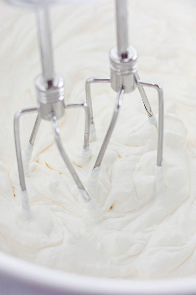 mixer whisks in a bowl with whipped cream 