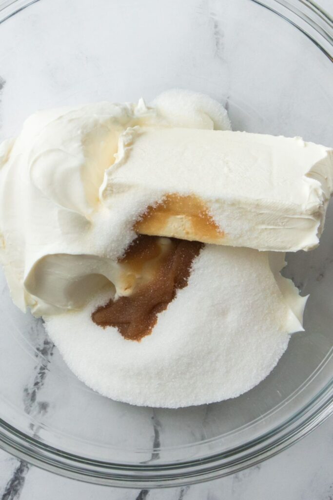 cream cheese, sour cream, granulated sugar and vanilla in a glass bowl on table