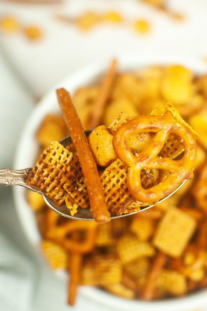 bowl of chex mix with spoon of chex mix on it 