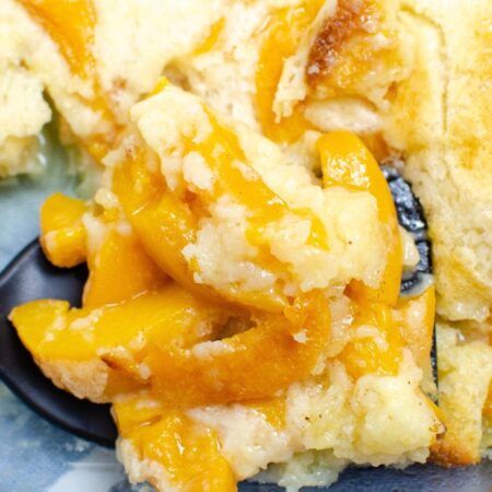 peach cobbler in pan with spoon under it