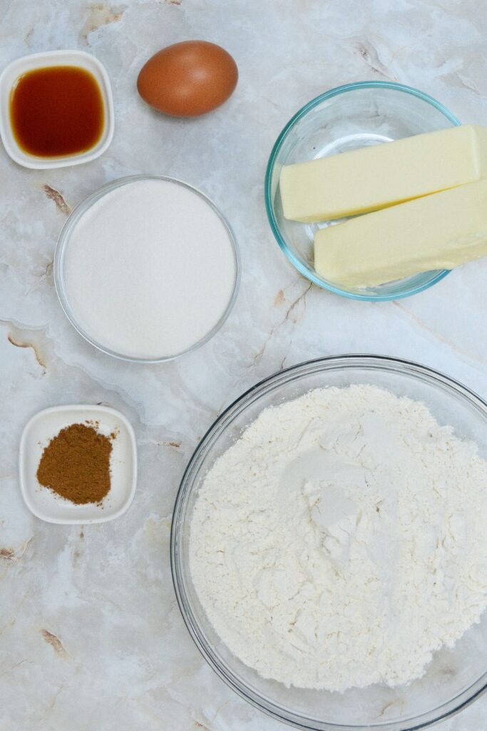 ingredients to make sugar cookies on table in glass bowls 