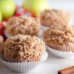 Apple Cinnamon Muffins on table with green apples in the background of image