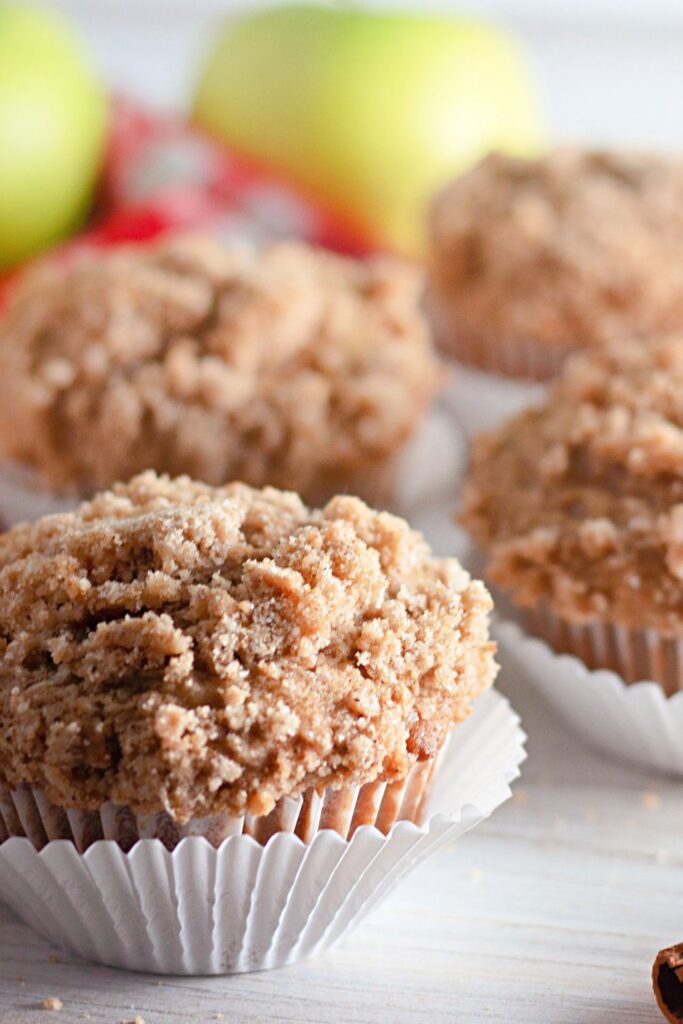 close up of apple muffins in muffin liners on table 