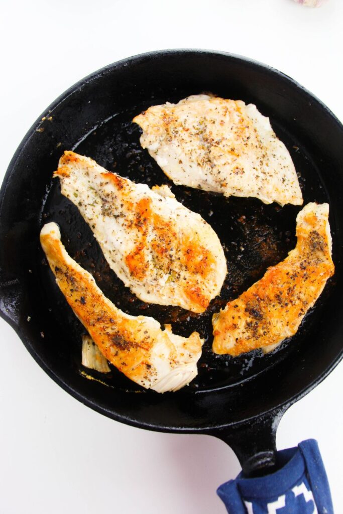 seared chicken in a cast iron skillet siting on a white table