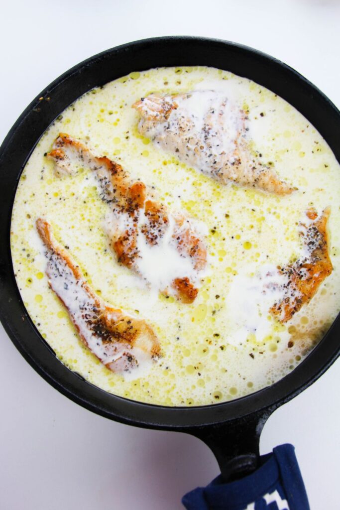 overhead look of skillet with chicken and a cream sauce in the pan 