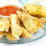 Homemade Air Fryer Mozzarella Sticks cooked and on a tray with a bowl of marinara sauce in a bowl on side