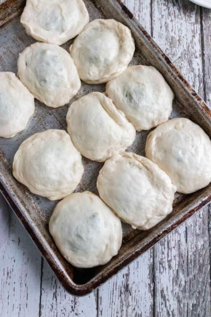 bierocks in raw form on a baking sheet on table 