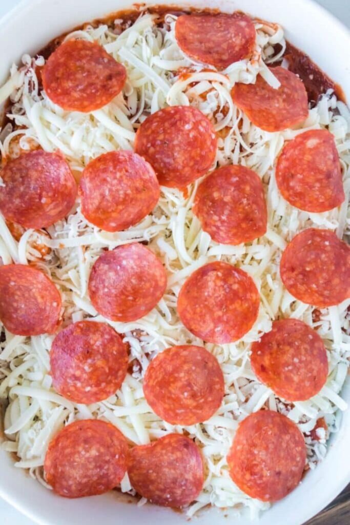 raw bubble bread pizza in a casserole pan topped with pepperoni slices 
