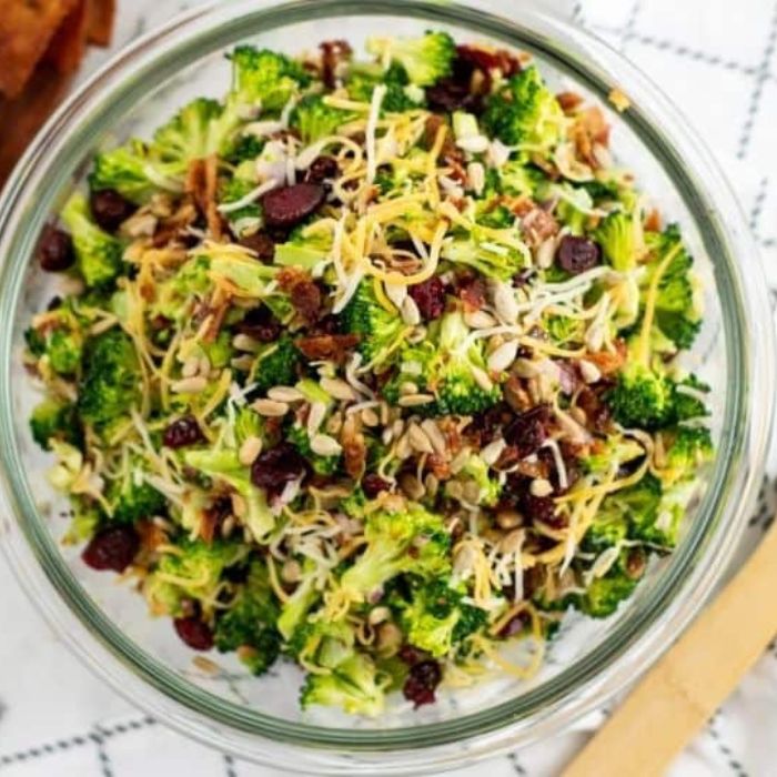 Amish Broccoli Salad in a bowl with a wooden spoon to the side of bowl