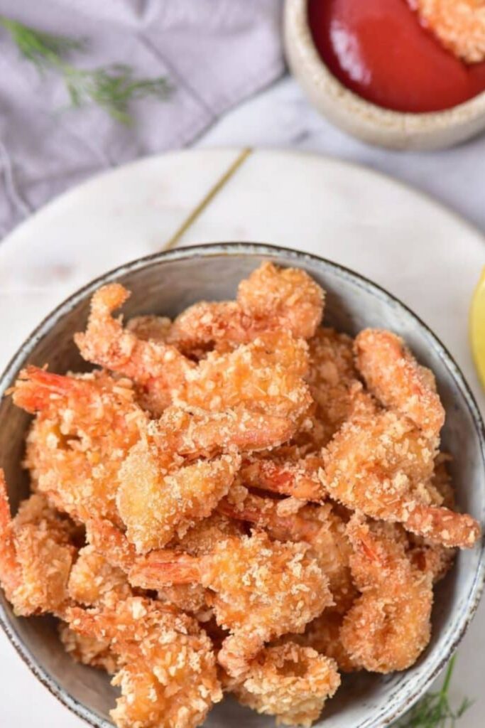 Fried Coconut Shrimp in a bowl with some dipping sauce to the side