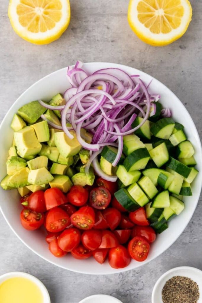 white bowl with red onions, cucumbers, tomatoes and avocado