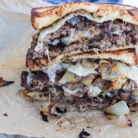 Blackstone Griddle Patty Melt Burger stacked on top of each other on table