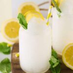 Lemonade Slushies in glasses sitting on table with lemons and mint around the table