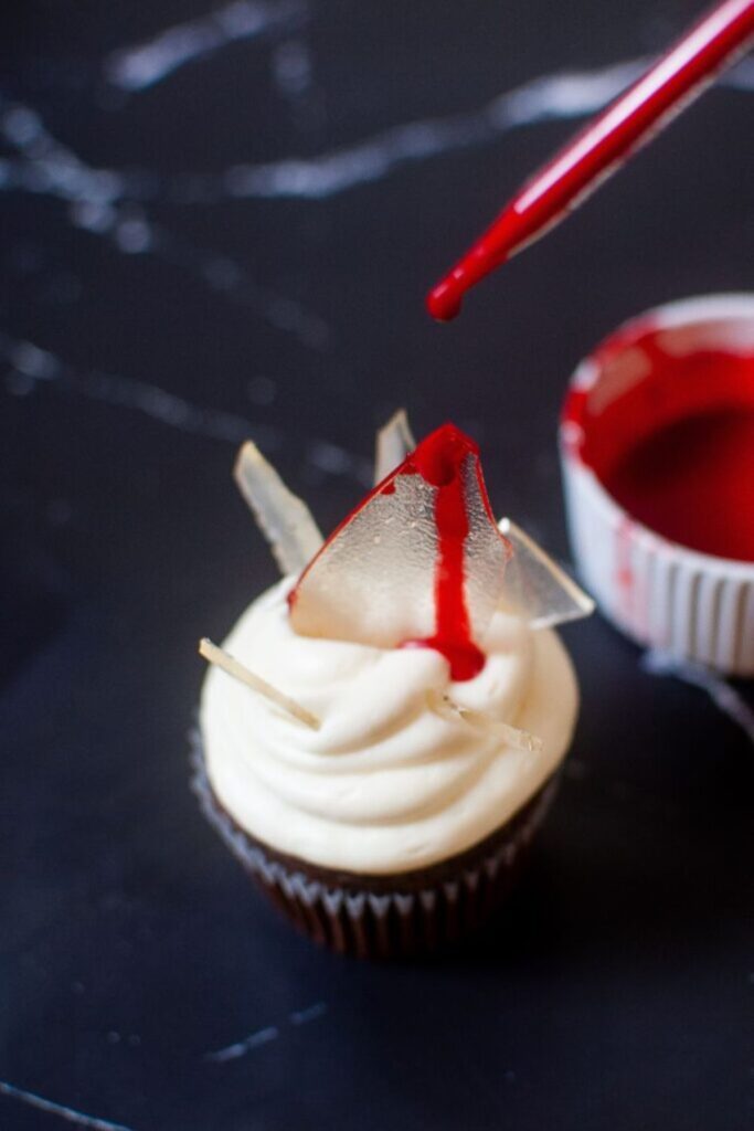 chocolate cupcake with fake glass and a drip of fake red blood on glass