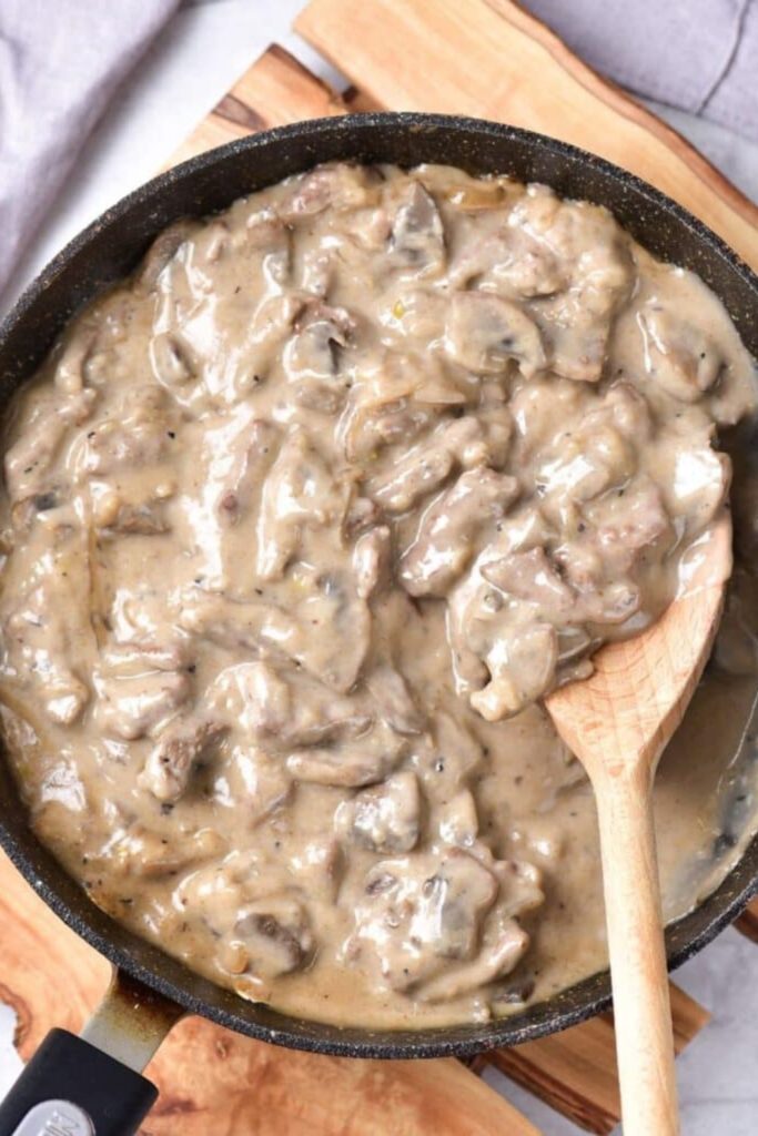 skillet of creamy beef stroganoff with a wooden spoon to the side