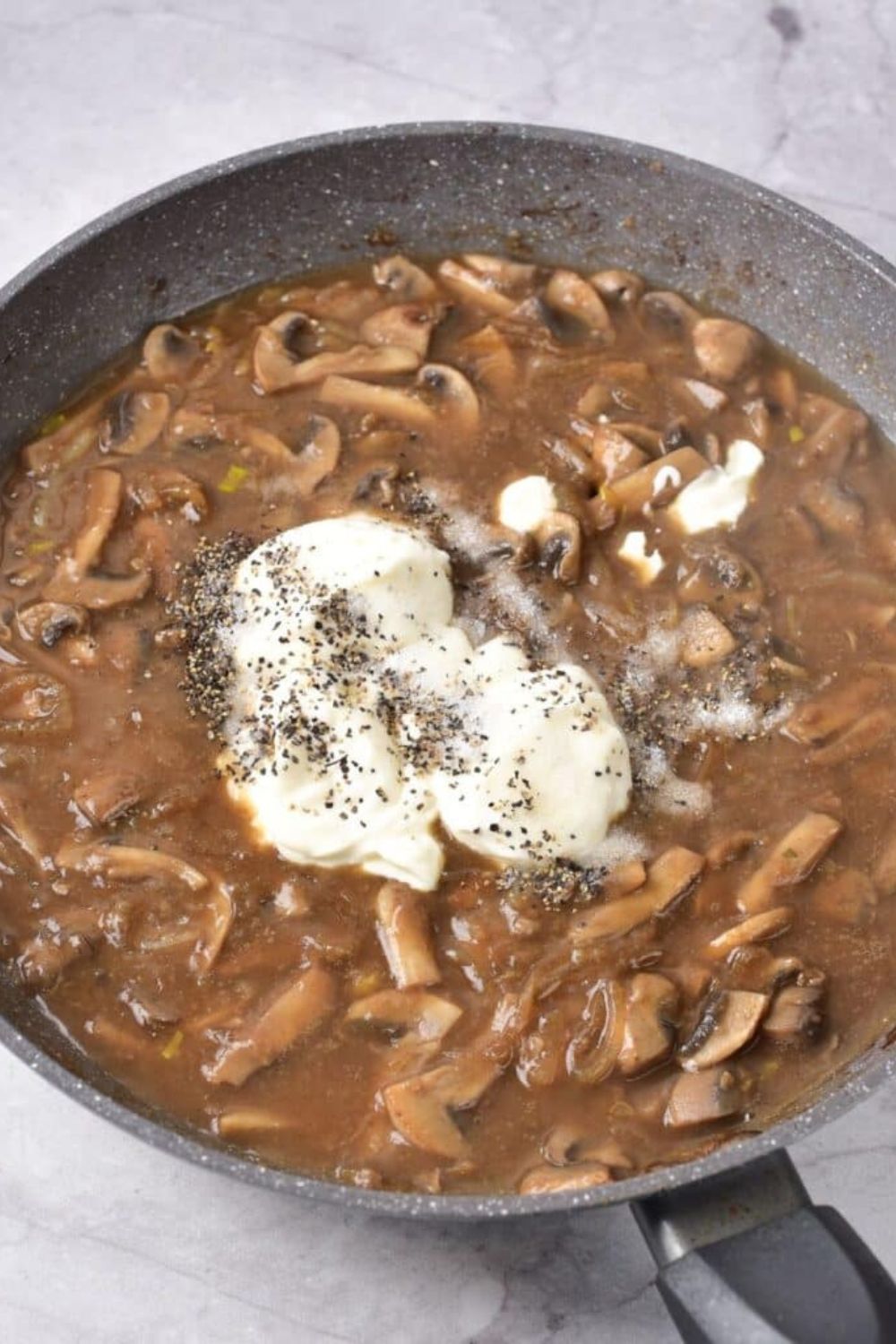 process of making Beef Stroganoff in a skillet that has meat mixture with sour cream in the center and seasonings