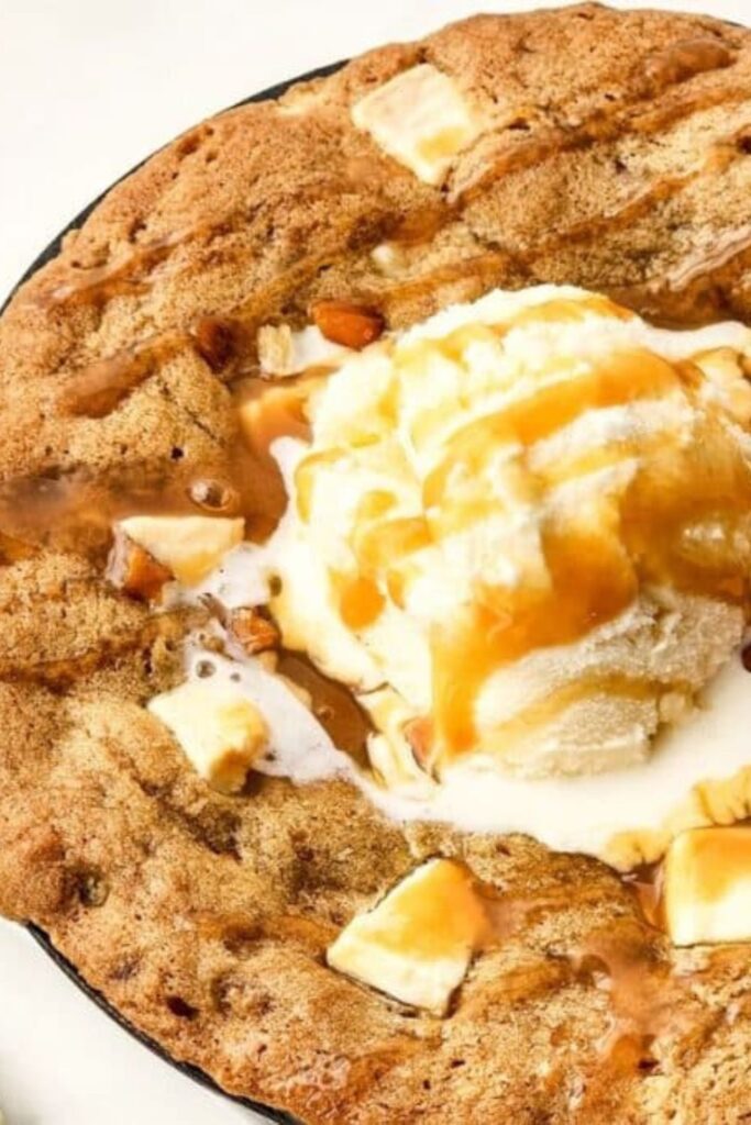 close up of a cast iron with Salted Caramel Cookie Skillet in it topped with ice cream and caramel sauce