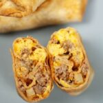 Breakfast Chimichangas stacked on top of one another with one cut in half and placed to side