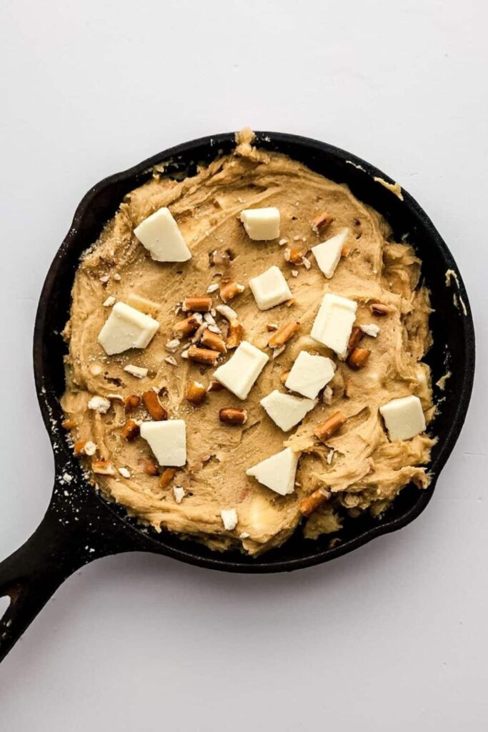 prep of Salted Caramel Cookie Skillet in a cast iron pan with butter and nuts on top