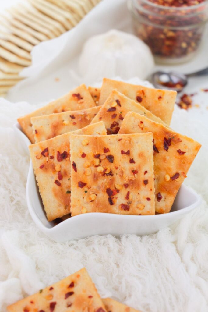 Alabama Heat Crackers in a white bowl on white table with some crackers placed to side of bowl