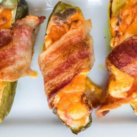 air fryer bacon wrapped pickles on a white tray on table all cooked
