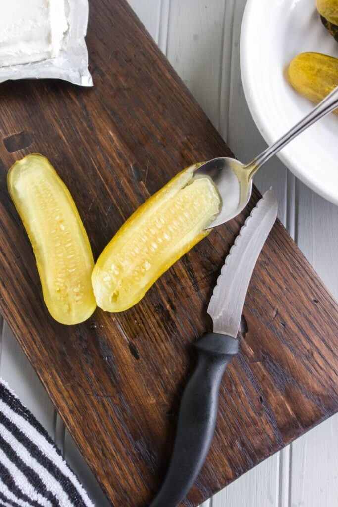 pickle being scraped out in the center on a wooden cutting board on the table