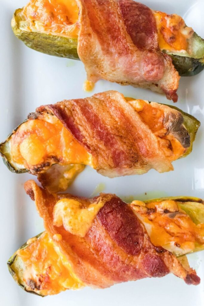 bacon wrapped pickles on a long rectangle white tray
