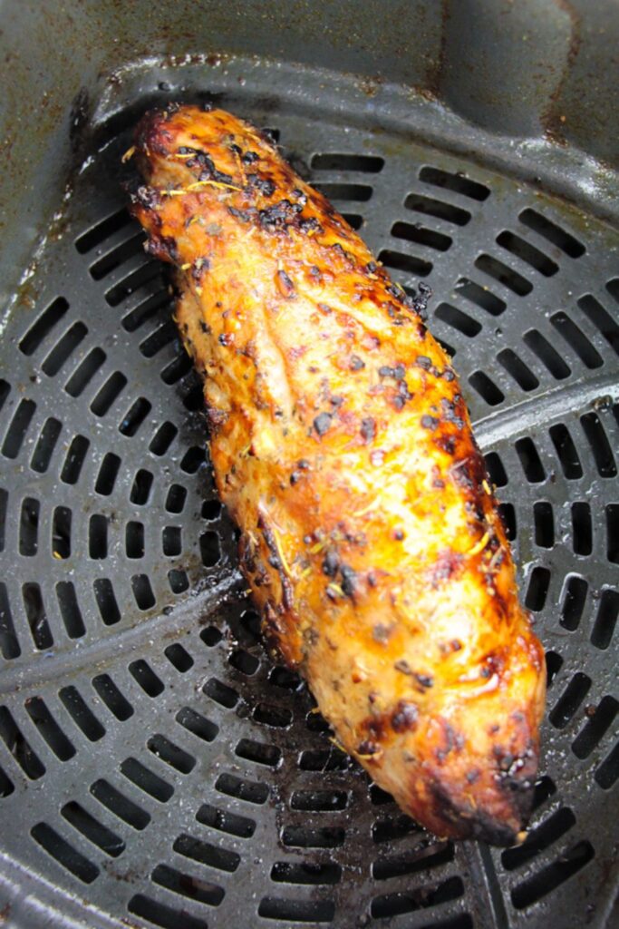 air fryer basket with a cooked pork tenderloin
