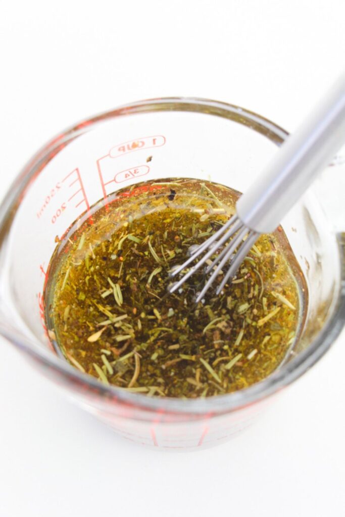 a mixing bowl with an oil based sauce with a whisk for marinated pork