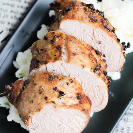 a black plate with some slices of cooked Marinated Air Fryer Pork Tenderloin