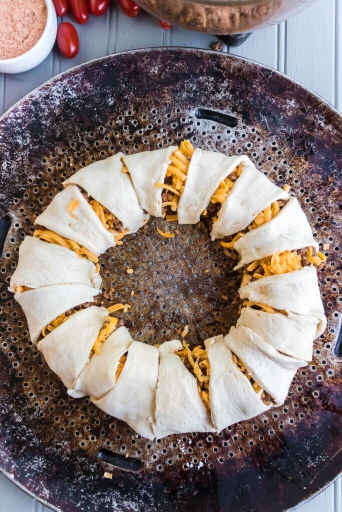 Taco Ring wrapped with crescent rolls on a baking sheet in raw form